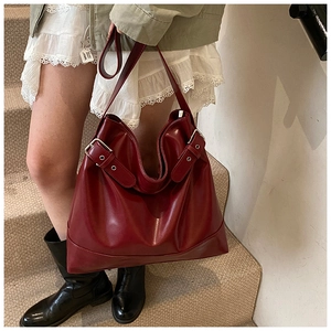 Detail of burgundy leather tote bag with glossy finish and metal buckle decoration