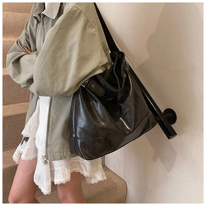 Detail of adjustable shoulder strap with silver eyelets on a black faux leather tote bag