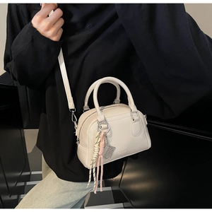 Detail of beige leather pillow bag with metal tennis racket charm and Choc Bird logo