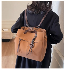 Detail of a brown vintage tote bag with unique knot pendant shown on model's shoulder