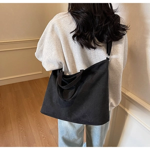 Detailed view of the large black canvas tote bag worn by a model in a home setting