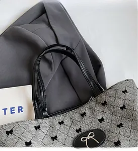 Détail du cabas matelassé gris avec imprimé nœud noir et poignée en cuir de qualité