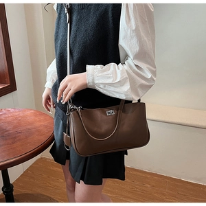 Close-up of a vintage brown leather shoulder bag with metallic buckle and zipper detail