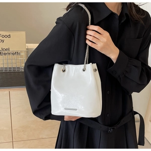 Modern white bucket bag detail with silver chain strap and minimalist metal logo plate
