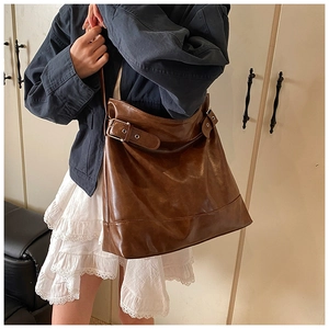 Detail of oil wax leather tote bag with metallic side buckle and adjustable strap