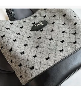 Gros plan du tissu matelassé gris avec motifs nœuds noirs et boucle dorée sur le sac