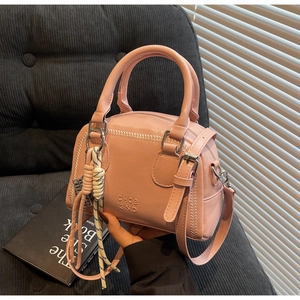 Detail of pink faux leather bag with lychee texture and woven rope charm decoration