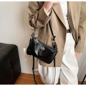 Detail of a black leather shoulder bag with a silver swivel clasp on a professional outfit