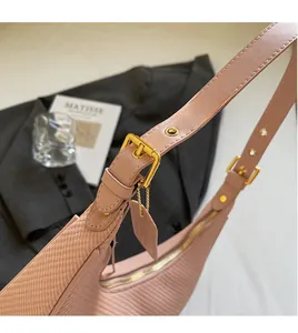 Close-up of pink crescent bag showing woven texture and adjustable strap with gold buckle