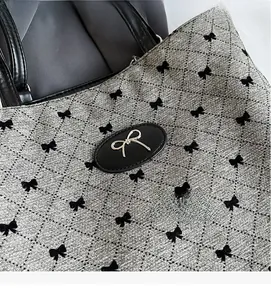 Gros plan du sac cabas matelassé argenté avec motifs de nœuds et logo en métal doré