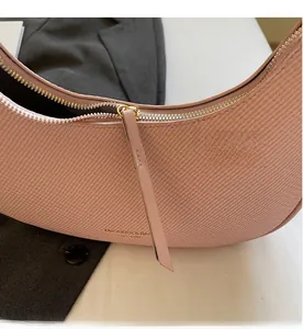 Close-up of pink crescent bag with smooth zipper detail and textured leather finish