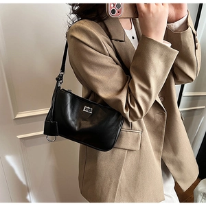 Classic black shoulder bag with silver buckle worn with a beige blazer for office style