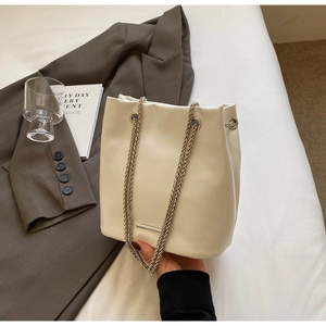 Detail of white leather bucket bag with silver chain straps and metallic bar decoration