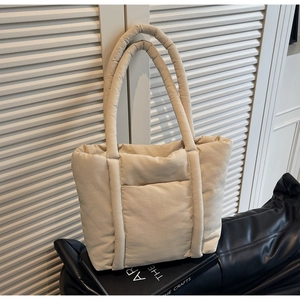 Dettaglio della borsa tote trapuntata beige con tasca frontale e consistenza morbida