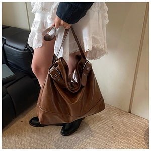 Detailed view of brown large-capacity tote bag with glossy leather and silver buckles