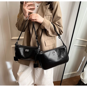Detail of minimalist black matte leather shoulder bags featuring square silver metal buckles