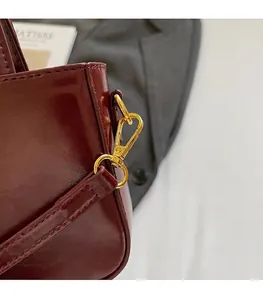 Detail van bordeauxrode laklederen tas met hoogwaardige goudkleurige metalen haken
