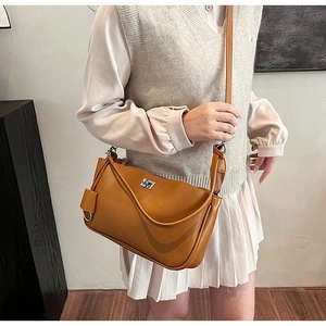 Detail of tan shoulder bag featuring polished silver turn-lock and leather hangtag
