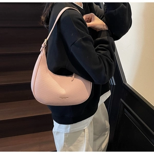 Detail of pink hobo bag with textured pattern shown on a person on wooden stairs