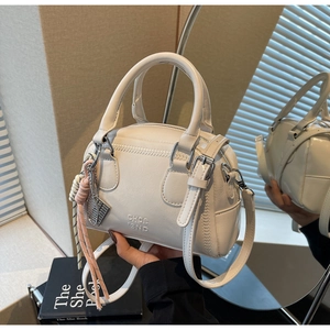 Detail of cream white leather pillow bag with CHOE BND embossing and woven rope charm