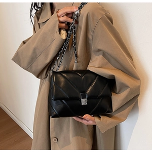 Detailed view of black chevron quilted crossbody bag with silver chain and metal lock