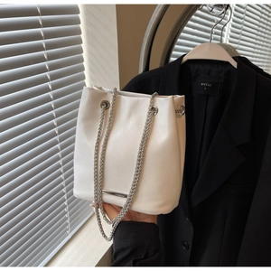 Detail of white lychee-patterned bucket bag with silver double chain and metal trim