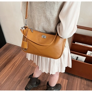 Detailed close-up of caramel brown leather shoulder bag with silver lock and long strap