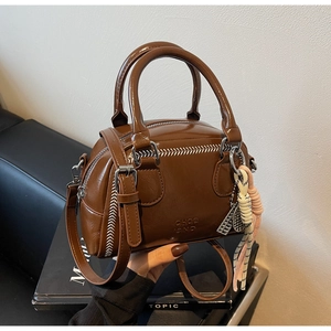 Detail of vintage brown leather pillow bag featuring white contrast stitching and tassel