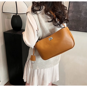 Close-up of a retro brown leather shoulder bag with a silver swivel lock on a model