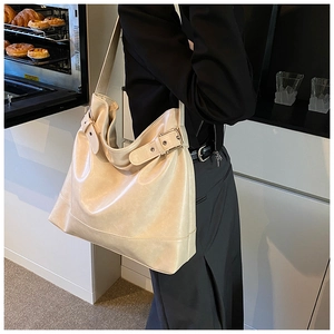 Detail view of large cream tote bag showing soft faux leather and side buckle adjustment
