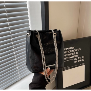 Detail of black faux leather bucket bag with silver chain strap and drawstring closure