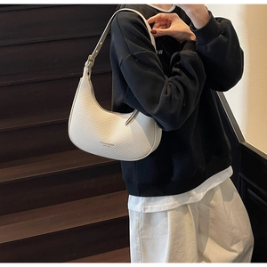 Detail of white woven leather crescent bag shown with casual streetwear outfit for style
