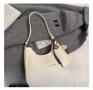Détail du sac demi-lune crème avec pendentif décoratif et bandoulière réglable chic