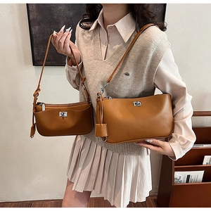 Detail of a brown leather shoulder bag featuring a polished silver metal twist-lock clasp