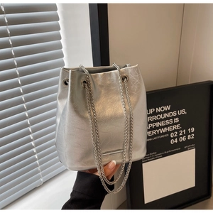 Detailed macro view of silver bucket bag featuring metallic cracked texture and chain straps