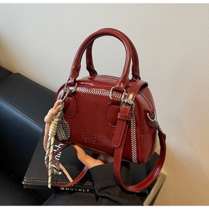 Macro shot of dark red leather bag with CHOC BND logo and white stitching detail