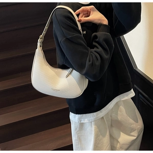 Close-up of white crescent moon bag featuring woven faux leather texture and adjustable strap