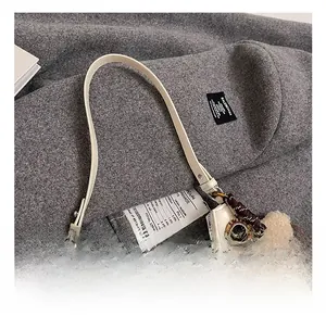 Détails macro du sac demi-lune blanc avec breloque argentée et cuir lisse de qualité