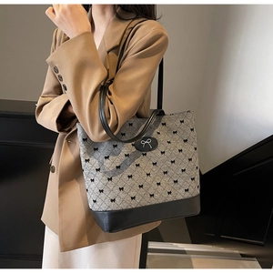 Détail d'un sac seau gris matelassé avec motifs nœuds noirs et lanières en cuir