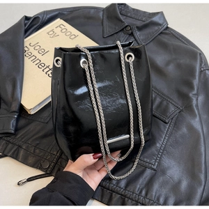 Close-up of black glossy leather bucket bag with metallic silver chain and detail