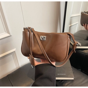 Detail of caramel brown leather shoulder bag with a silver square twist lock and strap