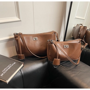 Detail view of two brown leather shoulder bags with silver twist locks on a sofa
