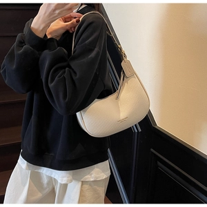 Detail of cream hobo bag with woven texture, golden metal logo and leather shoulder strap
