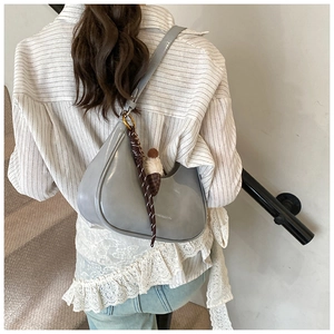 Détail du sac hobo gris avec breloque glace en peluche et ruban à carreaux sur un modèle