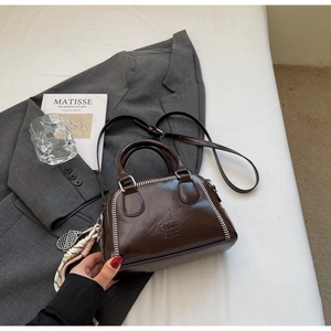 Detailed view of dark brown pillow bag with white whipstitch and tennis charm