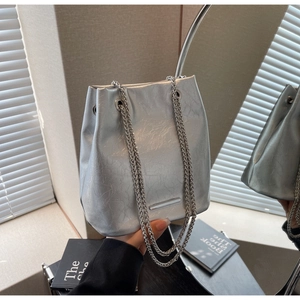 Detail of silver bucket bag with cracked texture and dual metallic chain straps