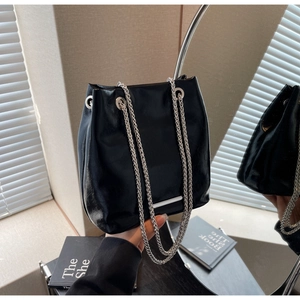 Detail of black glossy bucket bag with silver chain straps and metallic accents