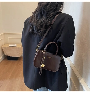 Detail van donkerbruine lederen crossbodytas met gouden hardware op een model