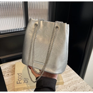 Detail of silver metallic bucket bag featuring soft pleated PU leather and chain straps