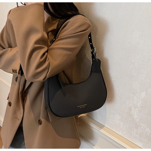 Detail view of the black crescent shoulder bag featuring fine diagonal textures and golden logo